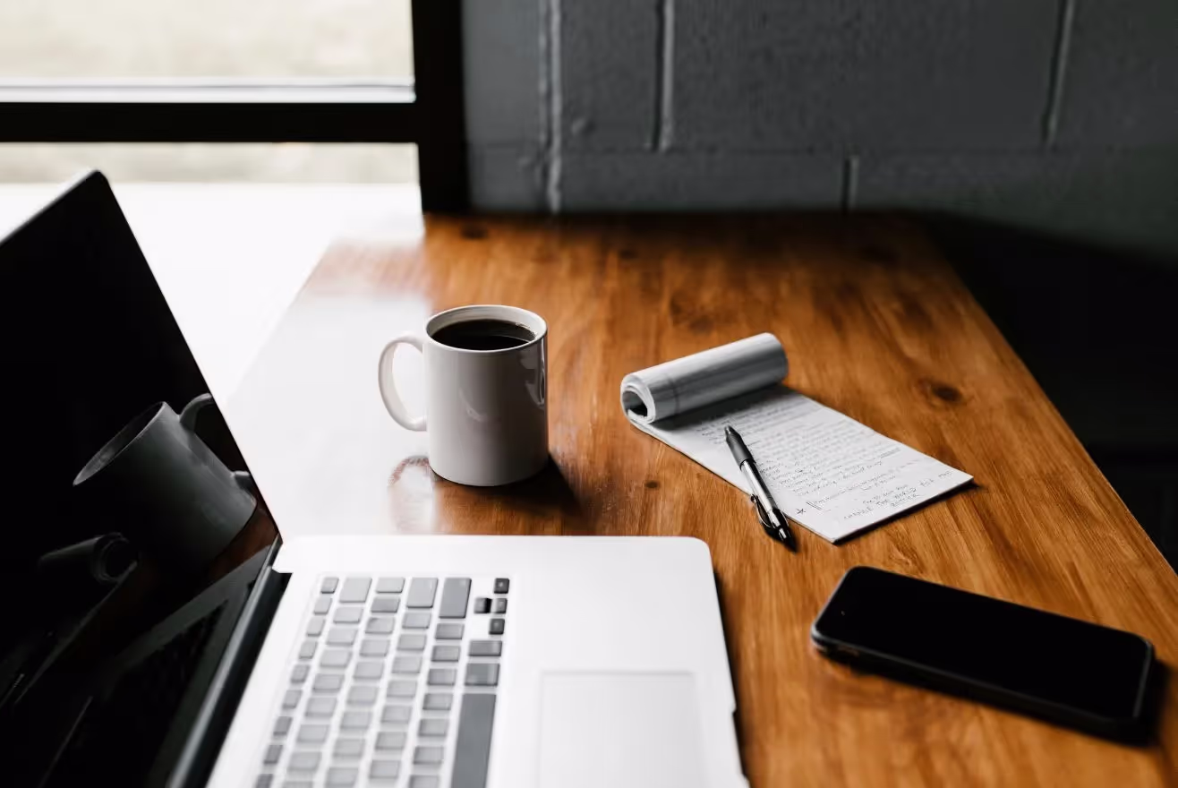 a laptop, coffee and notebook to show Management by BrandQuest